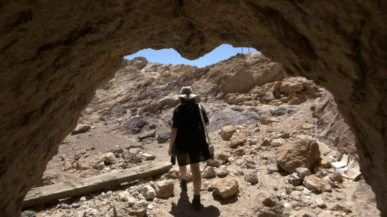 A young woman stepping out into the bright sun from a dark abandoned mineshaft Calico Ghost Town, California