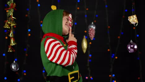 Kid-girl-in-Christmas-elf-Santa-helper-costume-dancing,-fooling-around.-New-Year-holiday-celebration