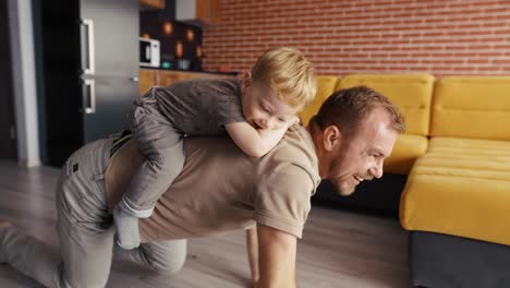 father playing with his son, riding him on the back at living room