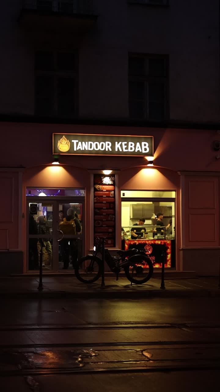 Ristorante Tandoor Kebab illuminato di notte con fattorino in attesa