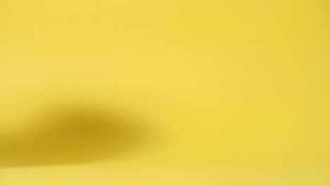 a reddish ceramic coffee mug taken by a hand, yellow backdrop in the background - static studio shot