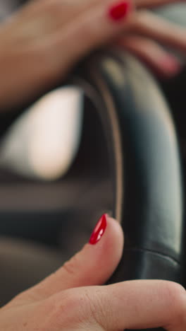 woman turns steering wheel of car to sides moving fingers on blurred background. female person with red nails enjoys driving vehicle closeup slow motion