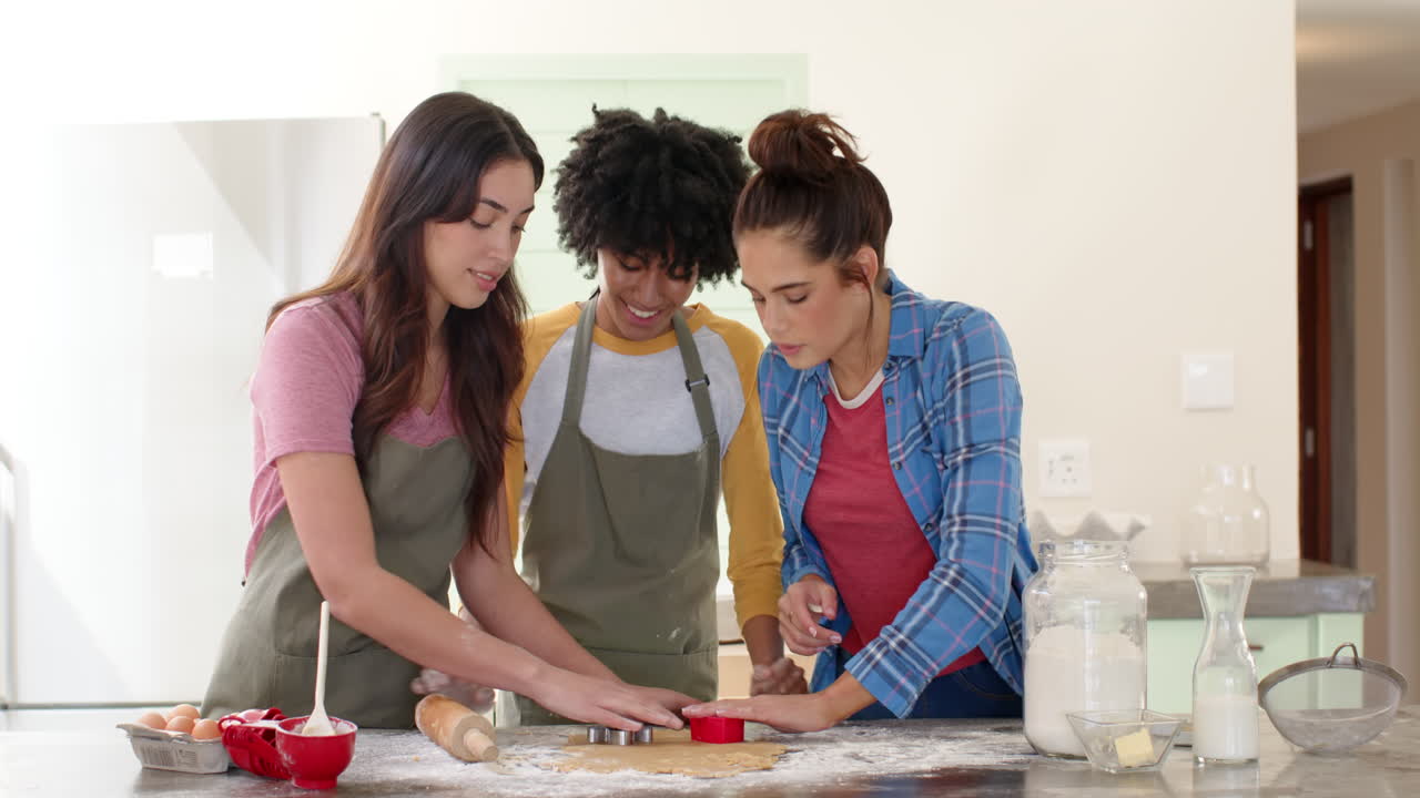 Women friends baking cookies together in kitchen, enjoying festive holiday preparations