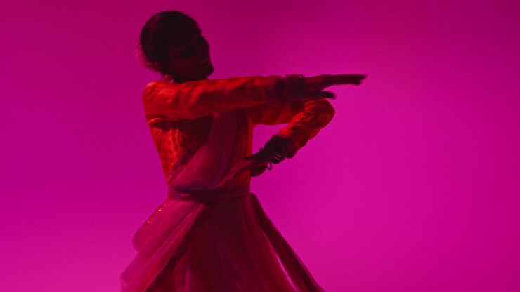 Spinning Female Kathak Dancer Performing Dance Wearing Traditional Indian Dress Against Purple Background
