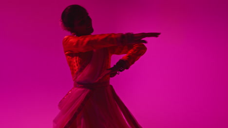 bailarina de kathak giratoria que realiza una danza vestida con el vestido tradicional indio contra un fondo púrpura