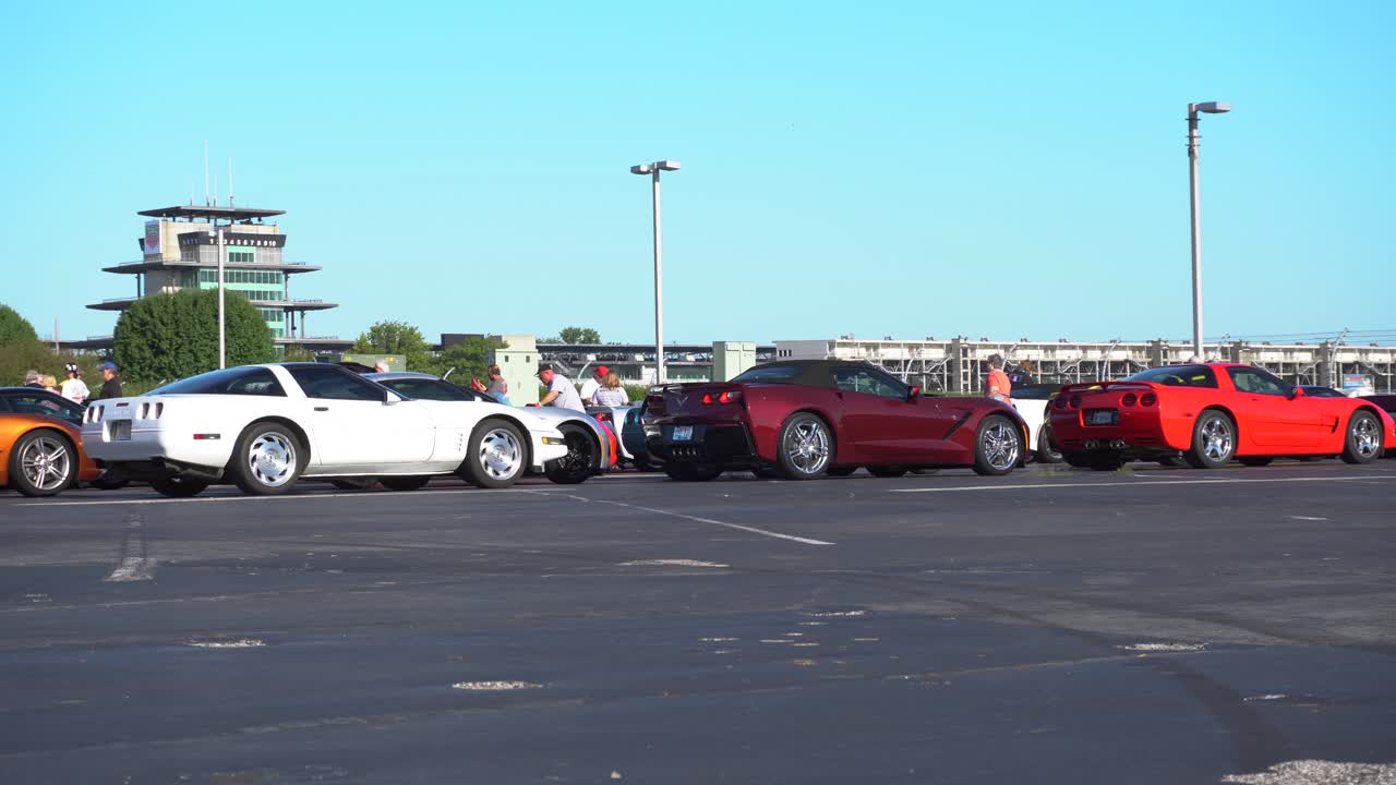 Quick pan across Corvettes parked together in formation. Features several generations of the iconic car.