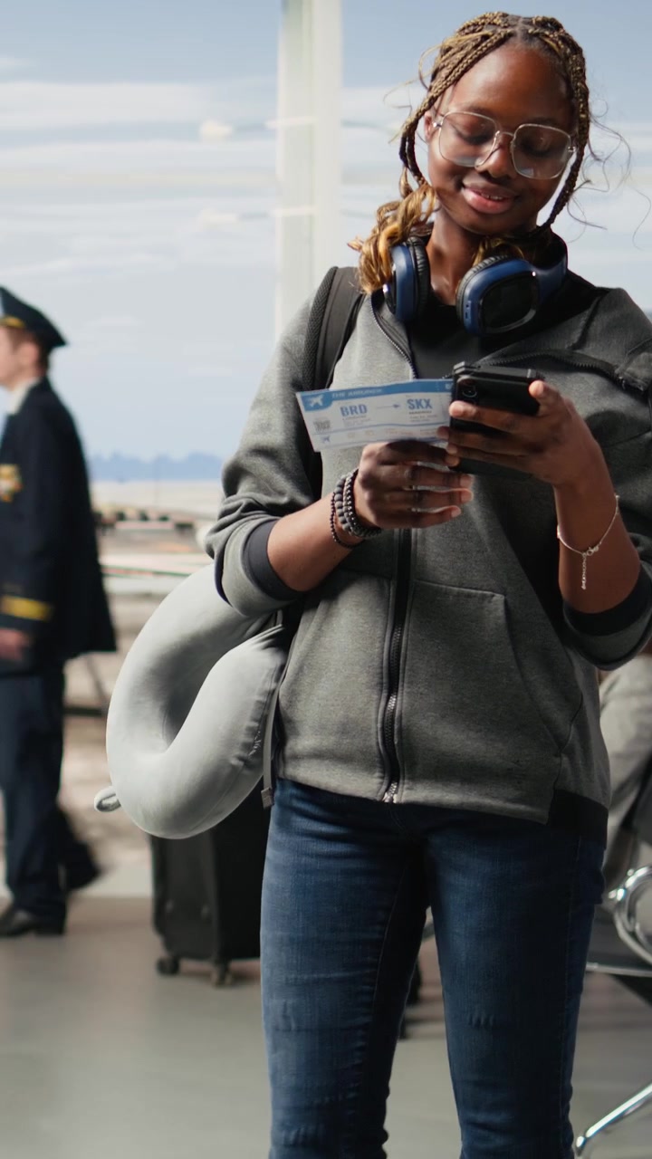 Video verticale: Donna viaggiatrice in piedi da sola in un moderno terminal aeroportuale