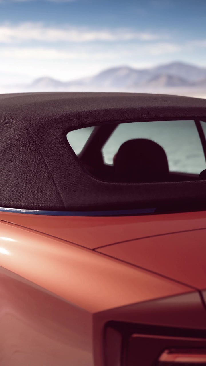 Cabriolet vicino all'acqua con montagne di giorno.