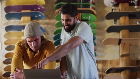 video of happy diverse male skateboarders fixing skateboard in skate shop