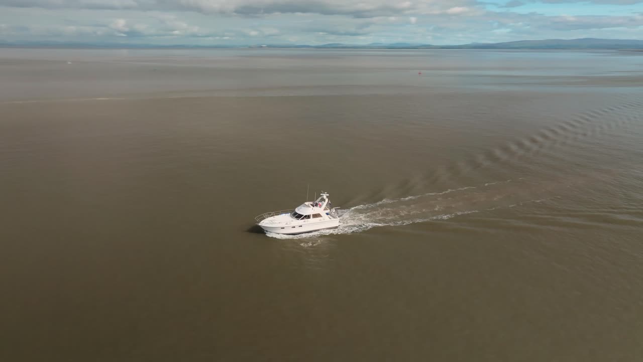 Motoscafo di lusso in acque calme e aperte con ripresa orbitale che mostra la costa e i riflessi. Fleetwood, Lancashire, Regno Unito