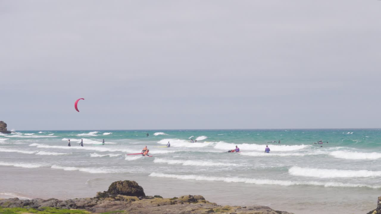 muchos surfistas y windsurfistas en el mar ventoso junto a la praia do guincho, portugal