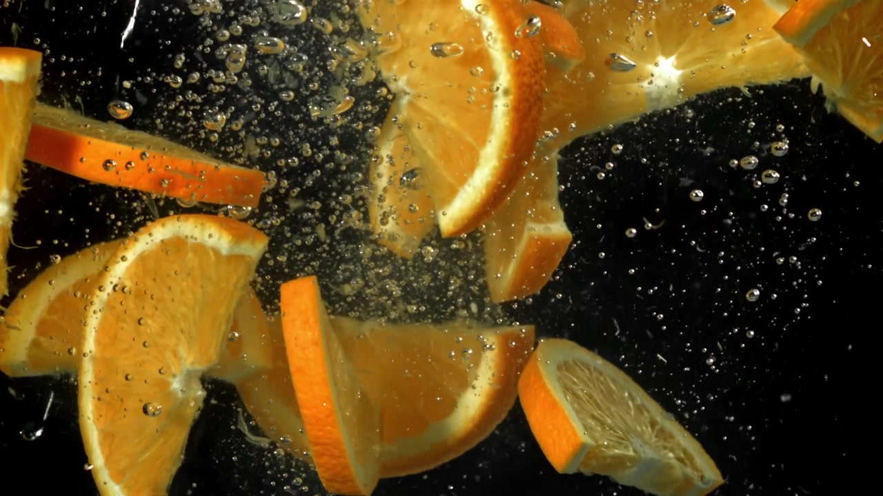 Fette fresche d'arancia che galleggiano in acqua limpida con bolle.