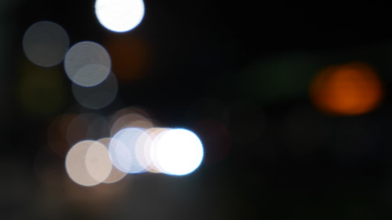 hermoso bokeh brillante en el fondo oscuro borroso por la noche. el redondo bokeh colorido brilla de las luces de los coches en la calle de la ciudad. fuera de foco con borroso. luces de la ciudad sin enfoque. bokeh de tráfico. concepto abstracto