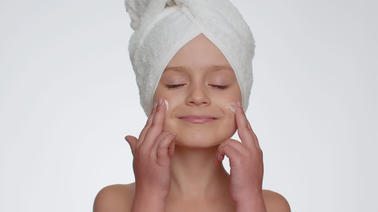 Sød ung pigebarn påfører rensende fugtgivende ansigtscreme, hudpleje med naturlig creme kosmetik
