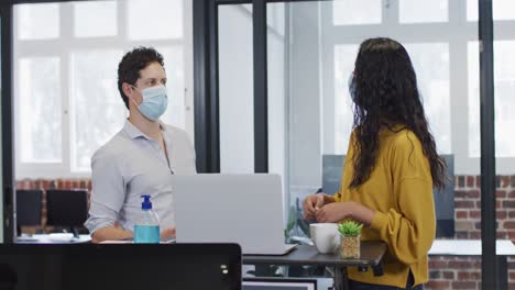 1374507hombre y mujer con máscaras faciales trabajando juntos en la oficina