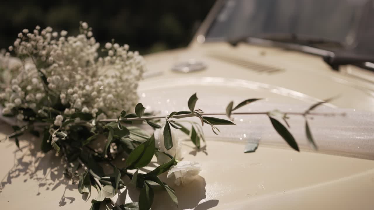 Close up of a vintage Volkswagen Beetle's hood, adorned with wedding flowers