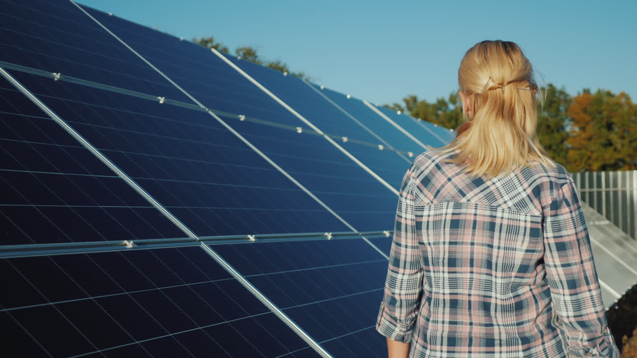 una mujer camina a lo largo de los paneles solares de una pequeña planta de energía solar doméstica