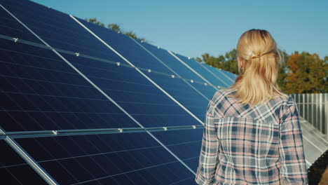 una mujer camina a lo largo de los paneles solares de una pequeña planta de energía solar doméstica