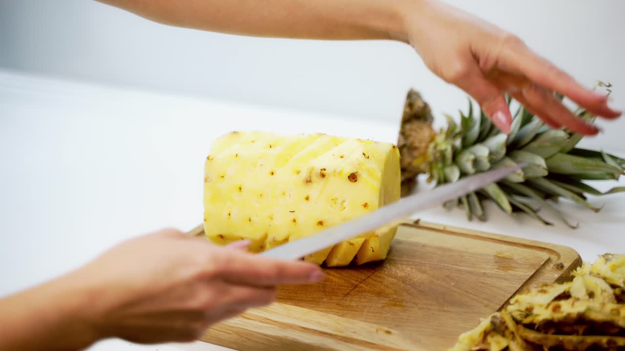 Hands slicing pineapple. Person slicing ripe pineapple with knife on table