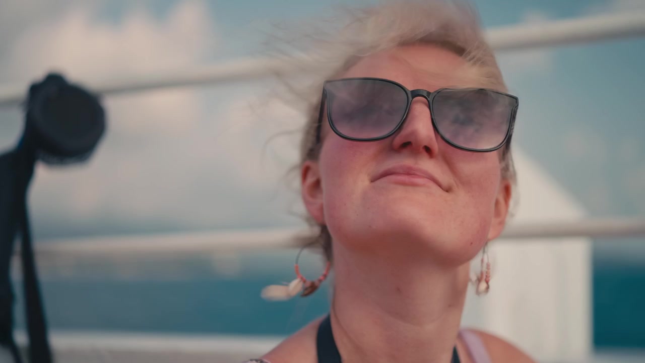 Leende blond kvinna i solglasögon på en båt till Koh Tao, Thailand.