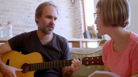 ather helping her daughter to play guitar in living room 4k