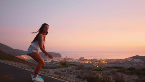 con las montañas como telón de fondo, una impresionante y elegante joven patinadora se desliza en su tabla en pantalones cortos a lo largo de una carretera de montaña al atardecer, todo capturado en cámara lenta