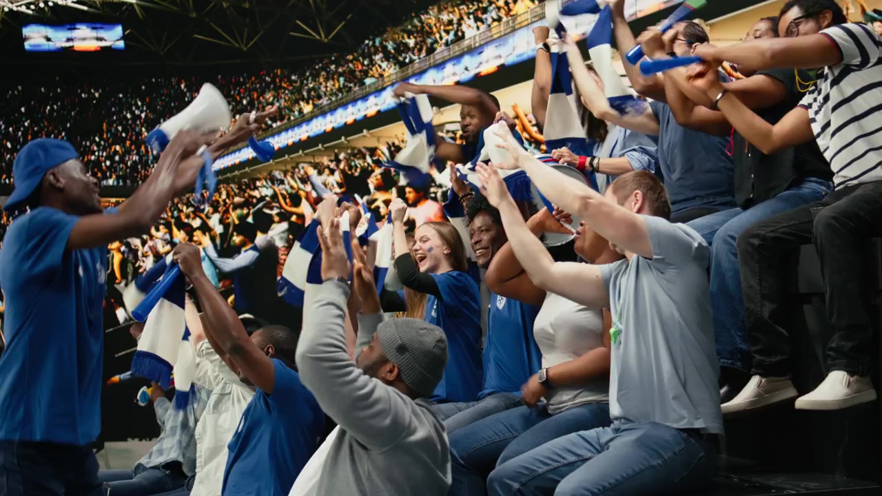Blue team football capo standing above crowd with megaphone