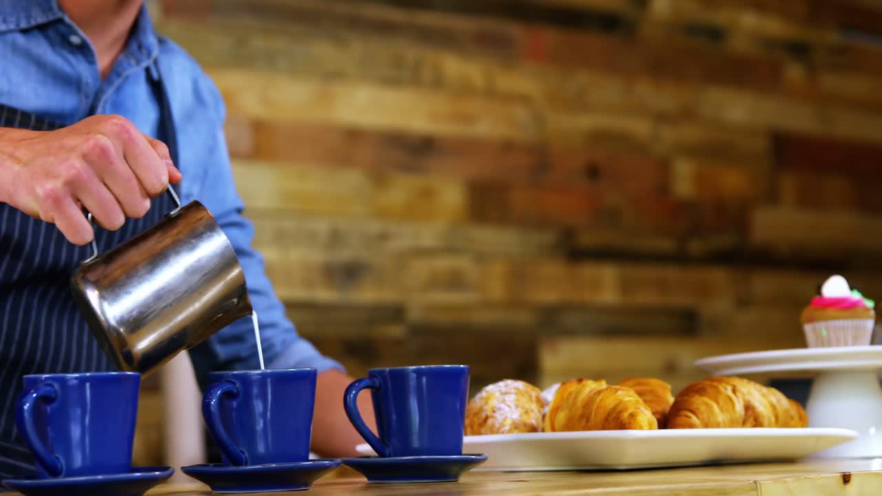 camarero vertiendo leche en el café en el mostrador