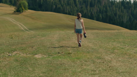 young girl photographer walking and shooting nature young photographer walking on green hill and shooting beautiful nature landscape girl filling the portfolio with amazing photos spending leisure time outdoor back view slow motion