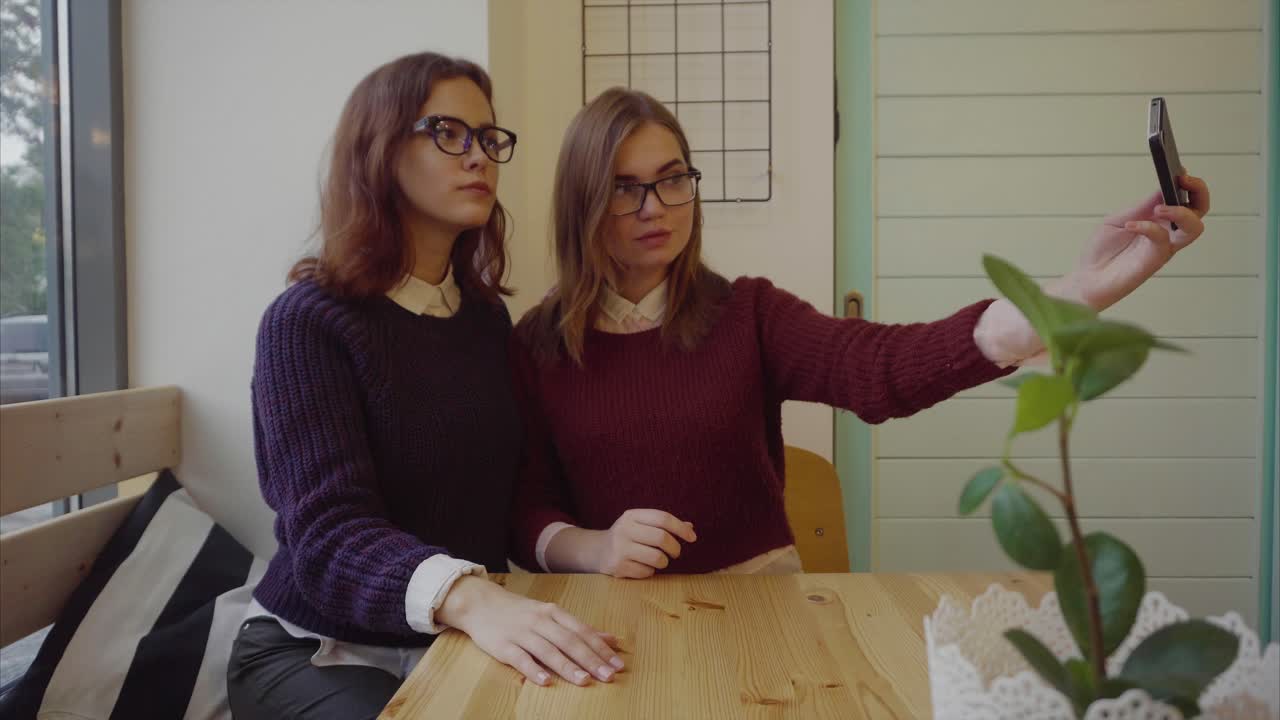 dos chicas tomando una selfie en un café