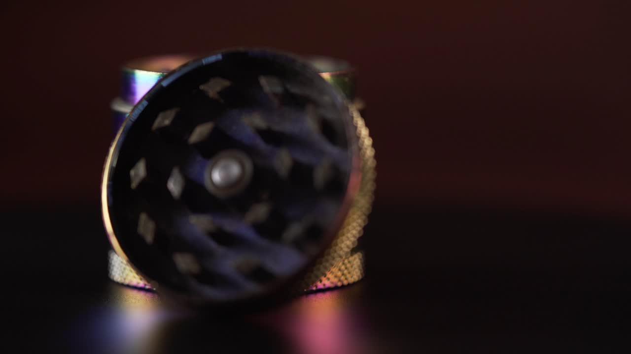 un molinillo de cannabis muy colorido sin la tapa y girando a la izquierda