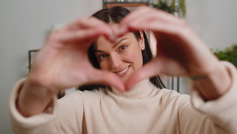 Una-Joven-Feliz-Hace-Un-Símbolo-De-Amor-Mostrando-Un-Signo-De-Corazón-A-La-Cámara-Expresa-Sentimientos-Románticos