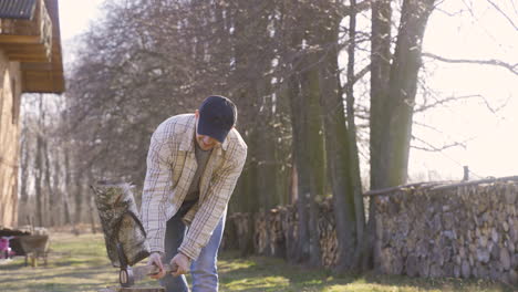 caucasian chopping firewood with an ax outside a country house