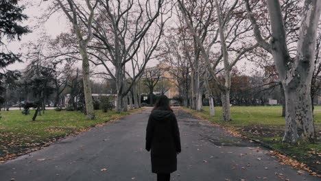 From-behind-high-shot-of-a-young-woman-walking-on-a-road-alone-then-stopping-and-turning-back