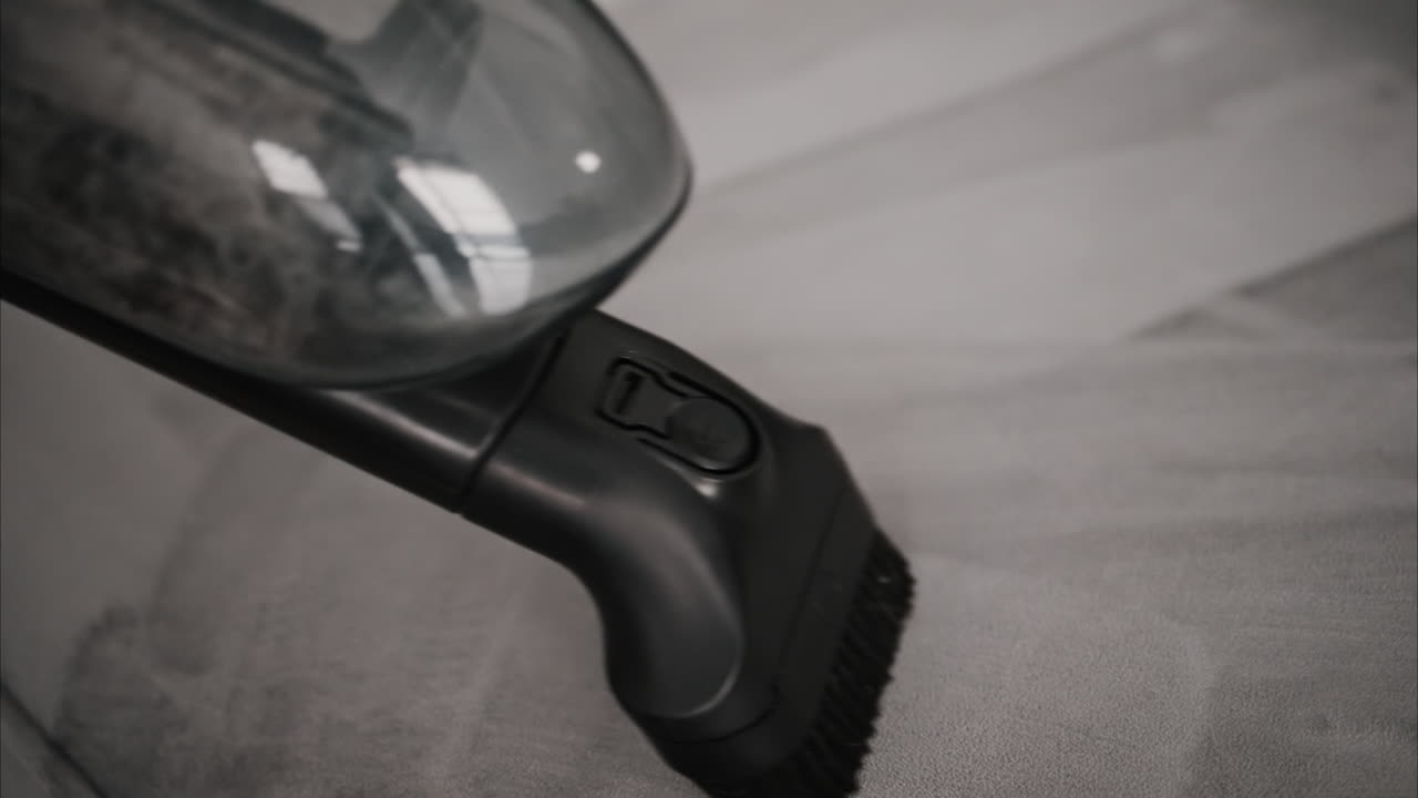 Close up of a small vacuum cleaning a grey couch