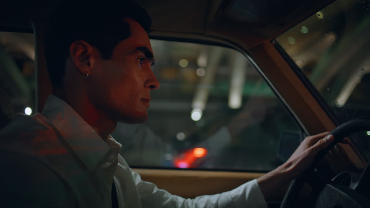 클래식 자동차를 타는 심각한 운전자 저녁 클로즈업. 자동차 을 들고 있는 남자