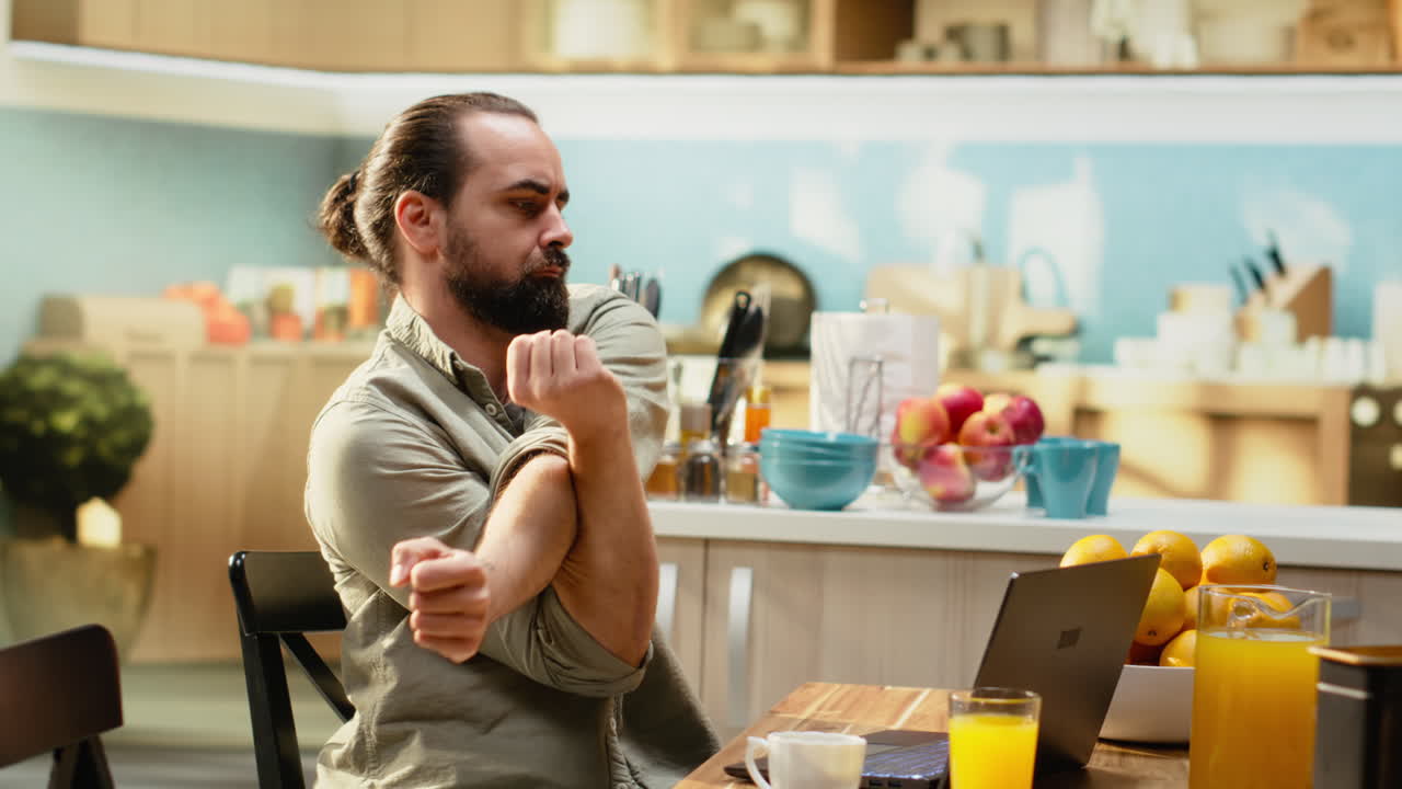Mandlig professionel strækker sine muskler og slapper af ved bordet