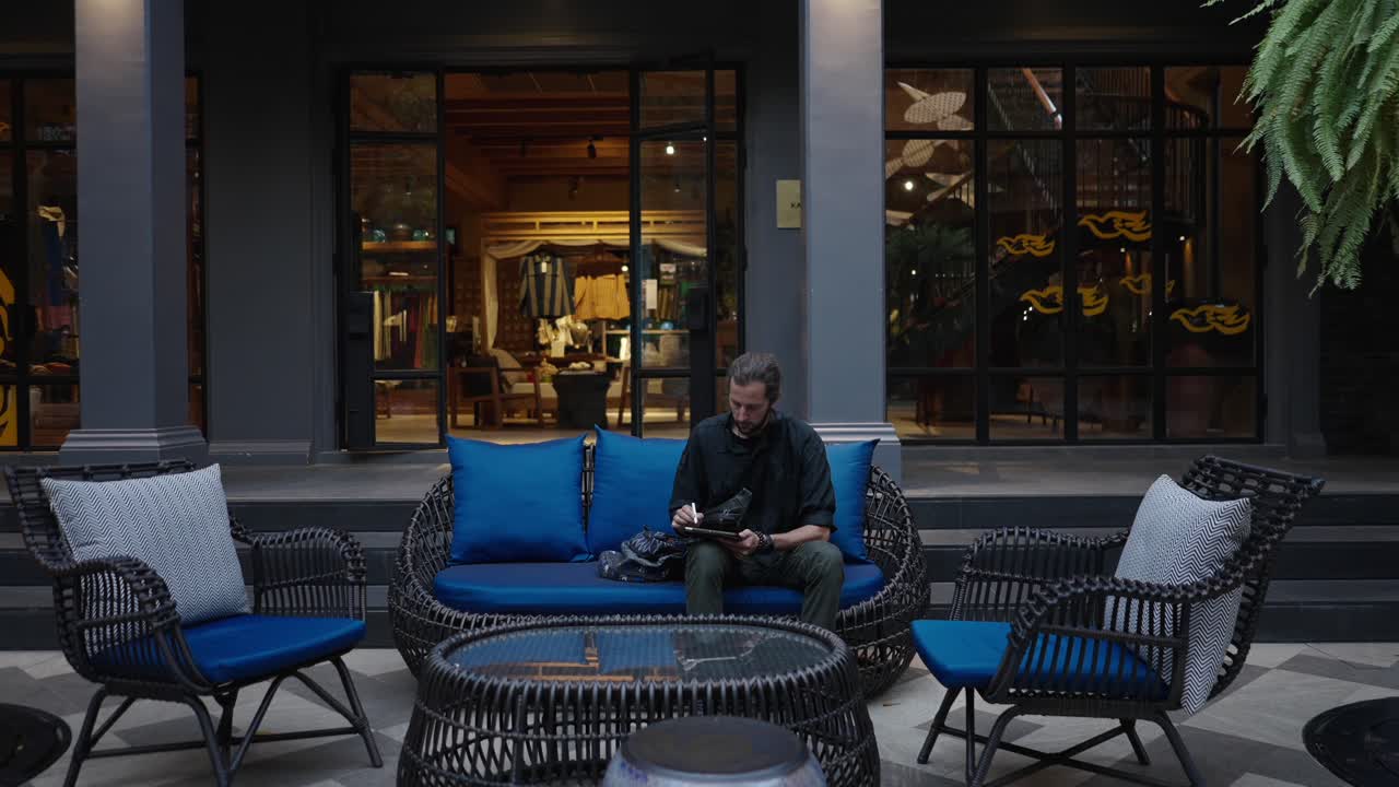 Man sitting on an outdoor sofa using a tablet