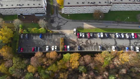 aerial bird's eye top-down view of a car parking lot near an apartment building in a neighborhood city area, wide shot