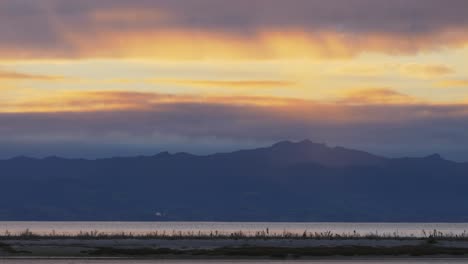 mountain silhouette, river and land, slow zooming out, sunset, long shot