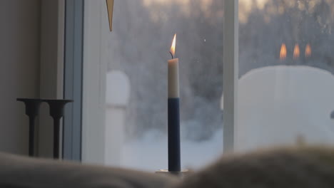 Vela-Símbolo-De-La-Independencia-De-Finlandia-Encendida,-El-Viento-Sopla-Nieve-Al-Aire-Libre-En-El-Fondo