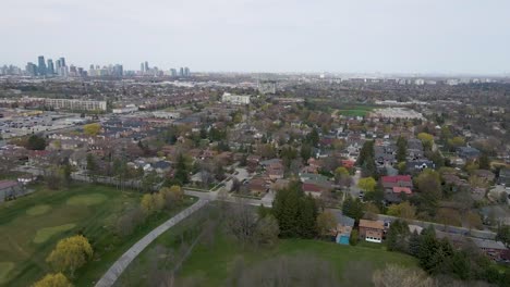 Drone-flying-over-the-edge-of-a-golf-course-towards-Mississauga-neighborhood-on-an-overcast-day
