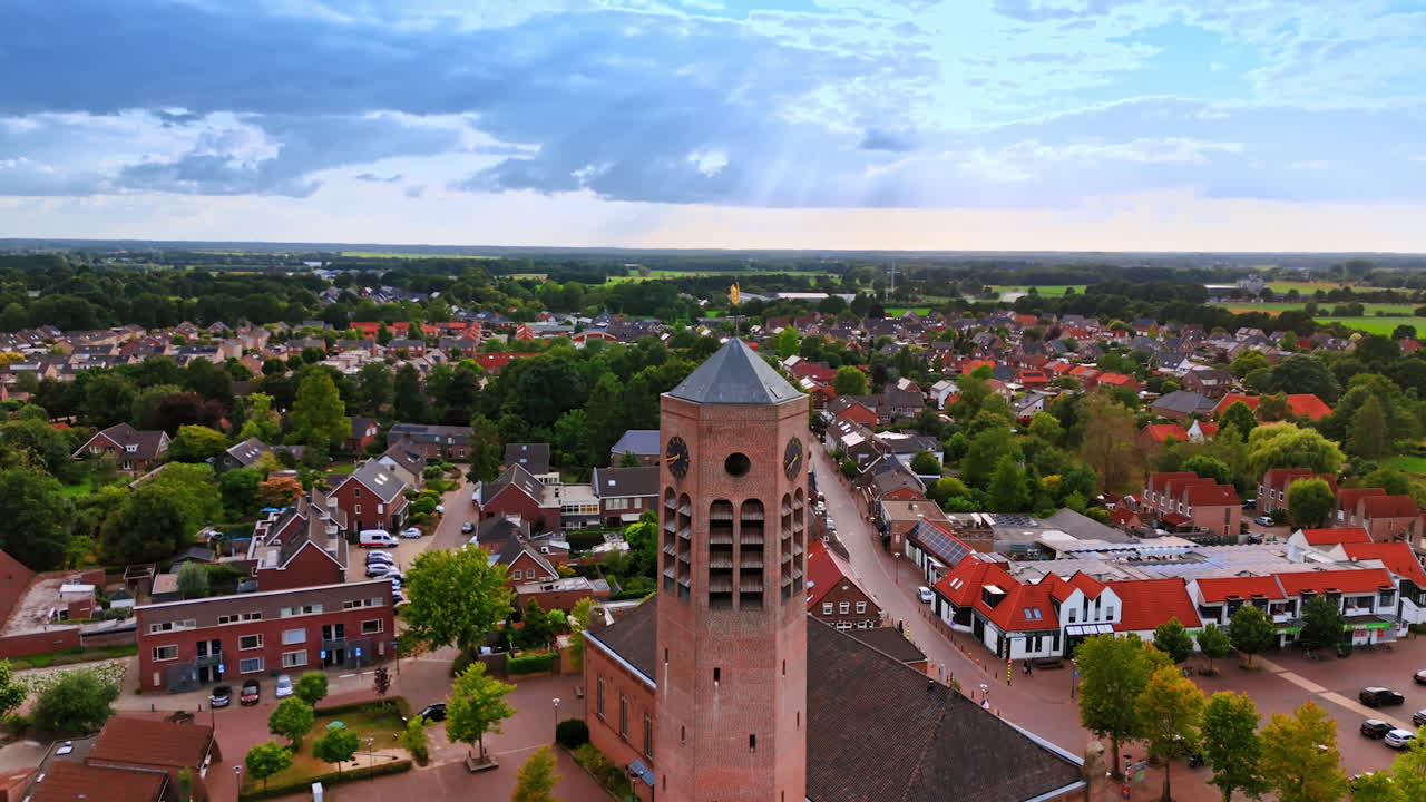 Distancing from a tall brick tower of the church with a weathercock on top. Scenery of the town in the Netherlands at backdrop