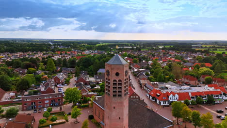 distancing from a tall brick tower of the church with a weathercock on top. scenery of the town in the netherlands at backdrop