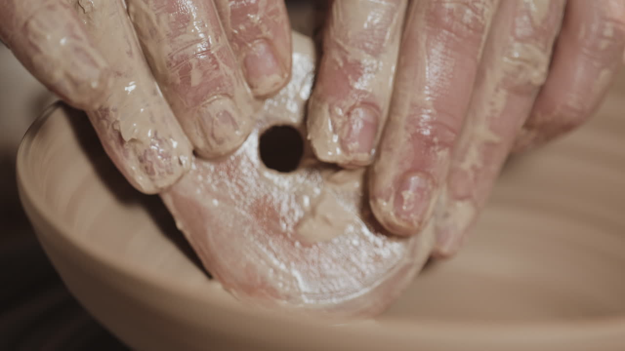 manos moldeando arcilla en una rueda de cerámica