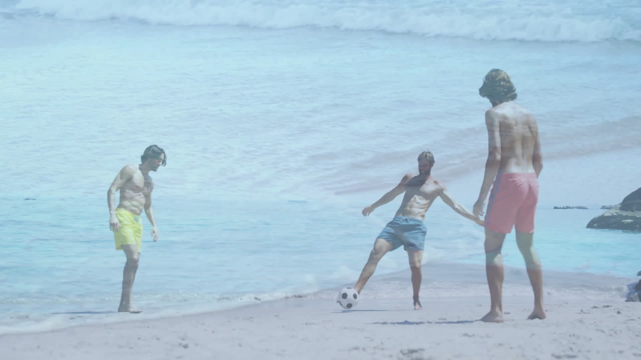Playing soccer on sandy beach, three people with ocean waves in background