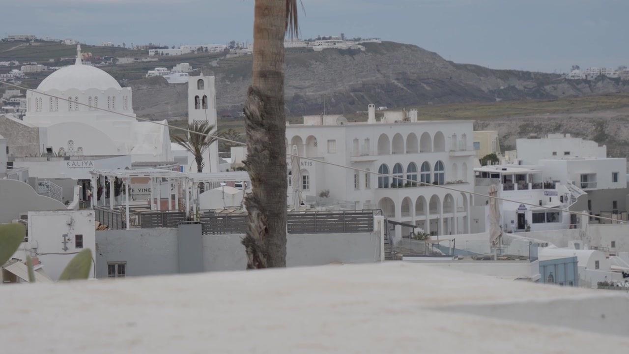 Fira, Santorini, Yunanistan'da volkanik kayalıkların altındaki yamaçta beyaz badanalı oteller ve binalar