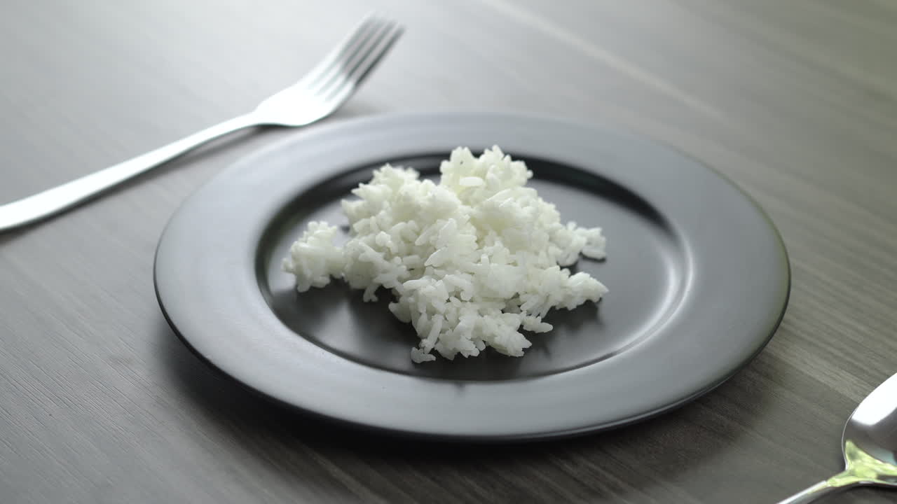 Scoop the rice and place it on a plate.Still life photography of food : Steamed Jasmine rice on white plate. Shooting in studio, Clean food good taste idea concept