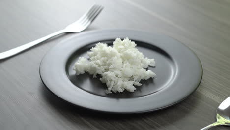 scoop the rice and place it on a plate.still life photography of food : steamed jasmine rice on white plate. shooting in studio, clean food good taste idea concept
