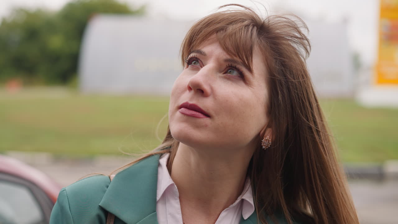 mujer pacífica con el cabello ondeando en el viento ligero mira hacia arriba